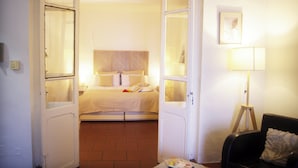 Een hotelkamer met een bed, een stoel, een lamp en een schilderij aan de muur.