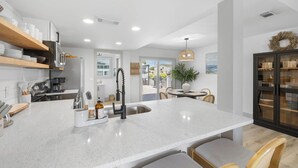 A modern kitchen with white countertops, a central island, and wooden shelves. - Bring your boat/Pool/Kayaks/Arcades (Hernando Beach)