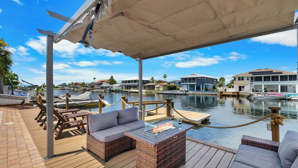 A wooden deck with outdoor seating, a fire pit, and a view of a marina with boats and buildings. - Bring your boat/Pool/Kayaks/Arcades (Hernando Beach)