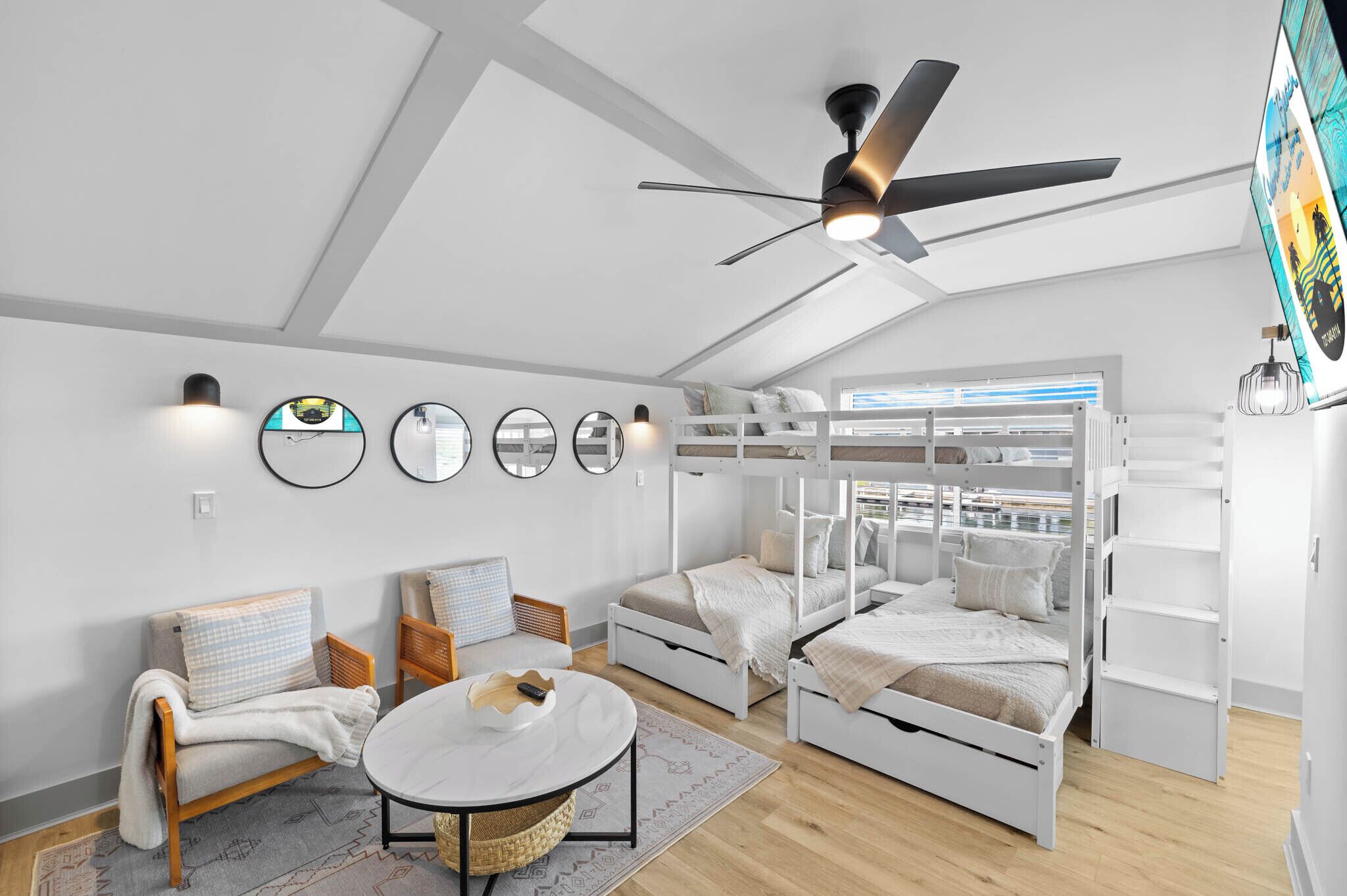 A modern bedroom with bunk beds, a round dining table, and a ceiling fan.