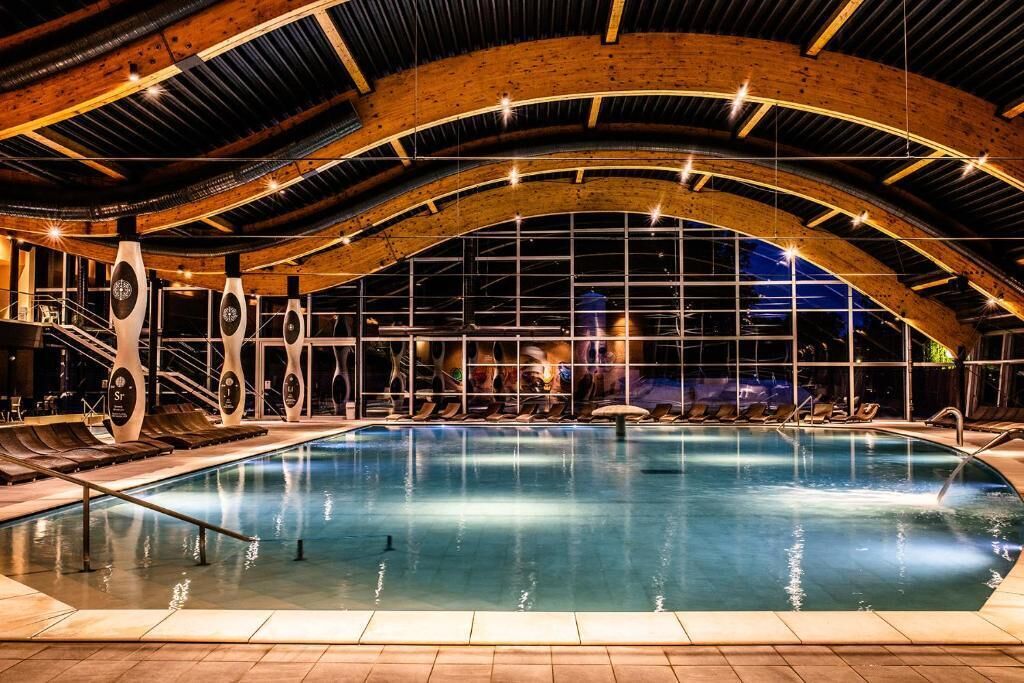 Una piscina interior con techo de madera y ventanas grandes.