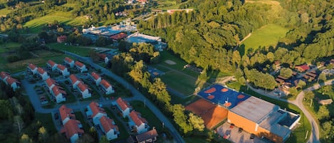 An aerial view of a residential area with houses, a sports field, and a large building with a red roof.