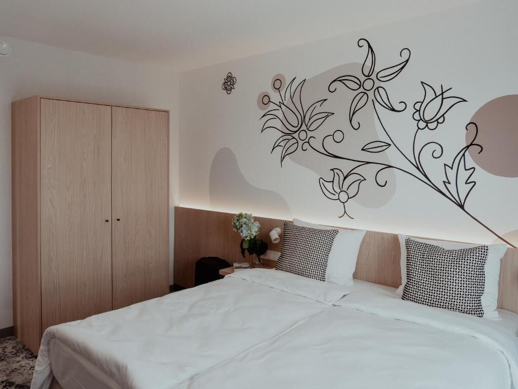 Une chambre à coucher comprenant un lit, une armoire et un mur orné d’un motif floral.