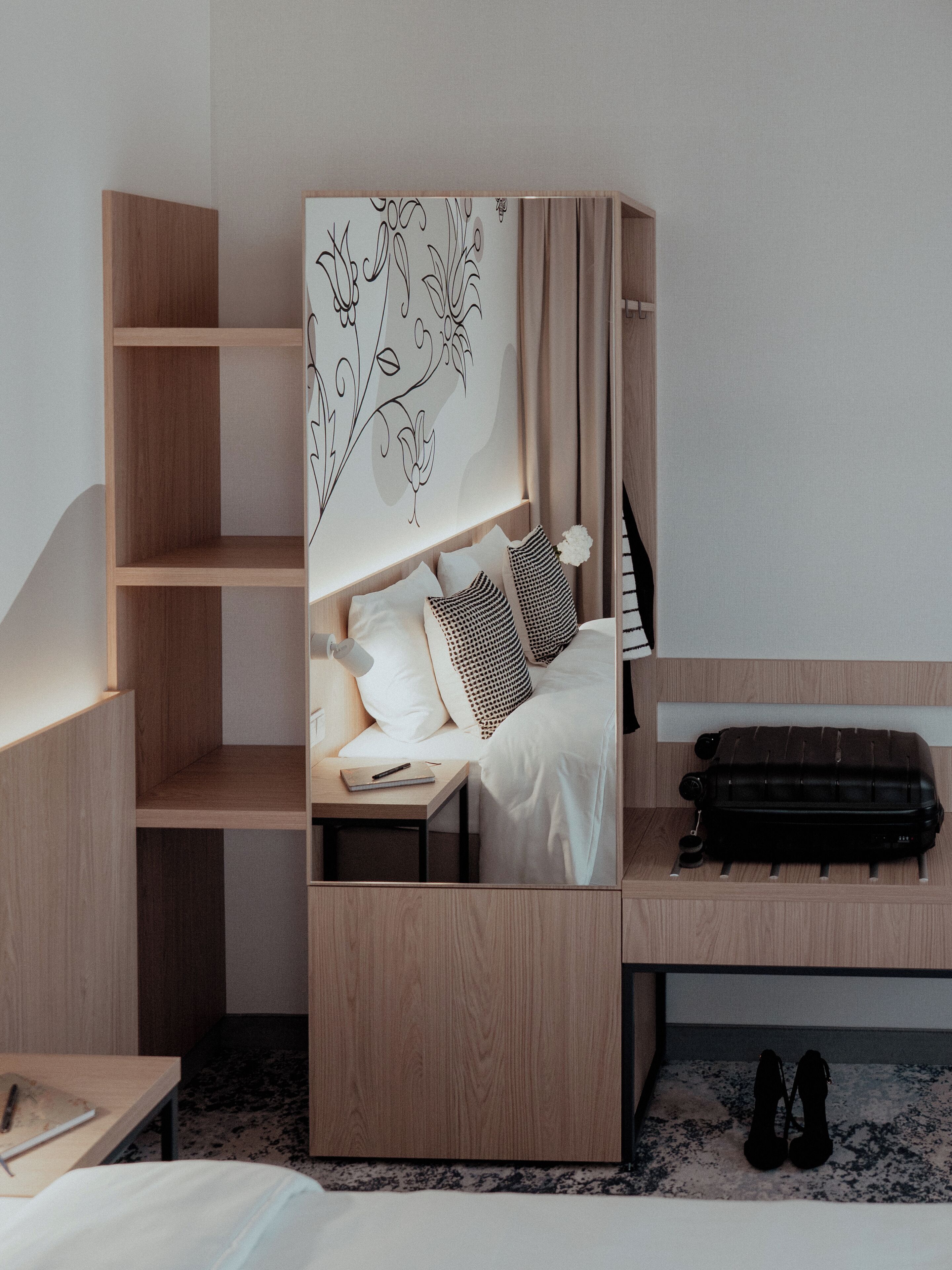 Een compacte, moderne slaapkamer met een bed, nachtkastje en een koffer.
