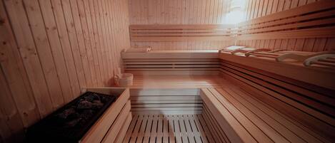 A sauna with wooden benches and a central heated floor.