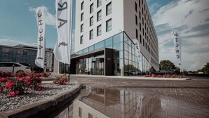 Un hotel moderno con fachada de vidrio, varios pisos y una entrada destacada.