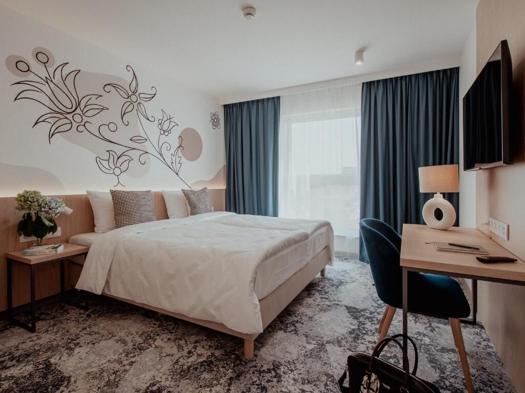 Una habitación de hotel moderna con una cama grande, un escritorio y un televisor.