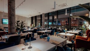 Un interior de restaurante moderno con techos altos, ventanas amplias y diferentes opciones de asientos.