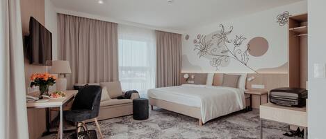 A modern hotel room with a bed, desk, chair, and a decorative wall.