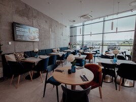Un restaurante moderno con pared de concreto, sillas azul y naranja, y mesas con manteles blancos.