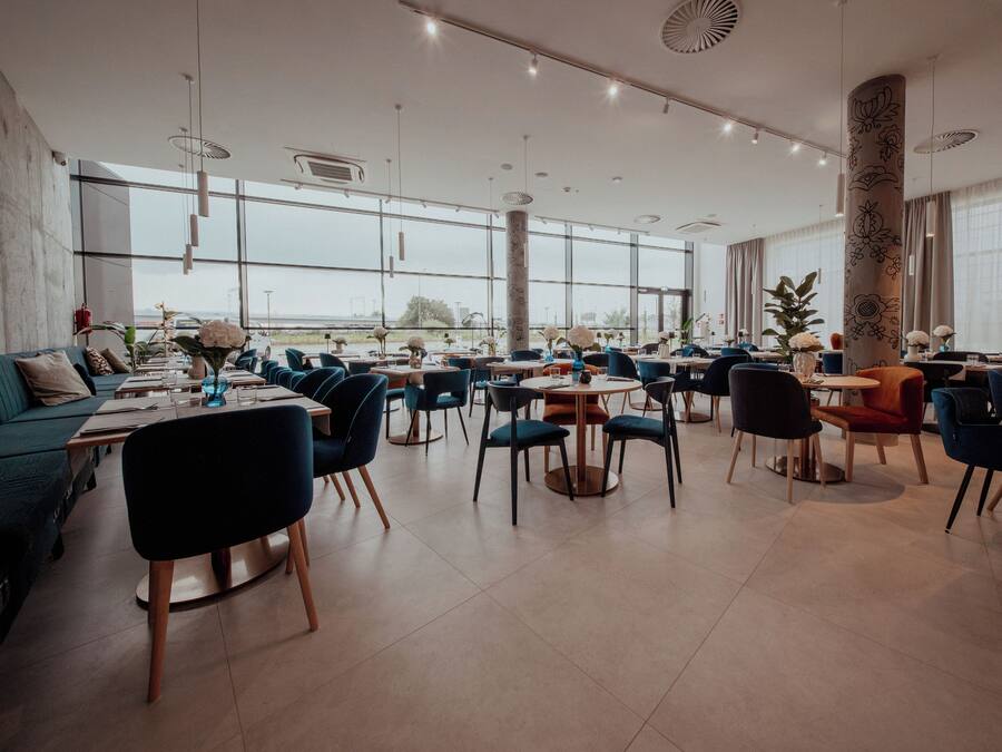 Ein großzügiges Restaurant mit hohen Decken, großen Fenstern und einer Mischung aus moderner und klassischer Einrichtung.