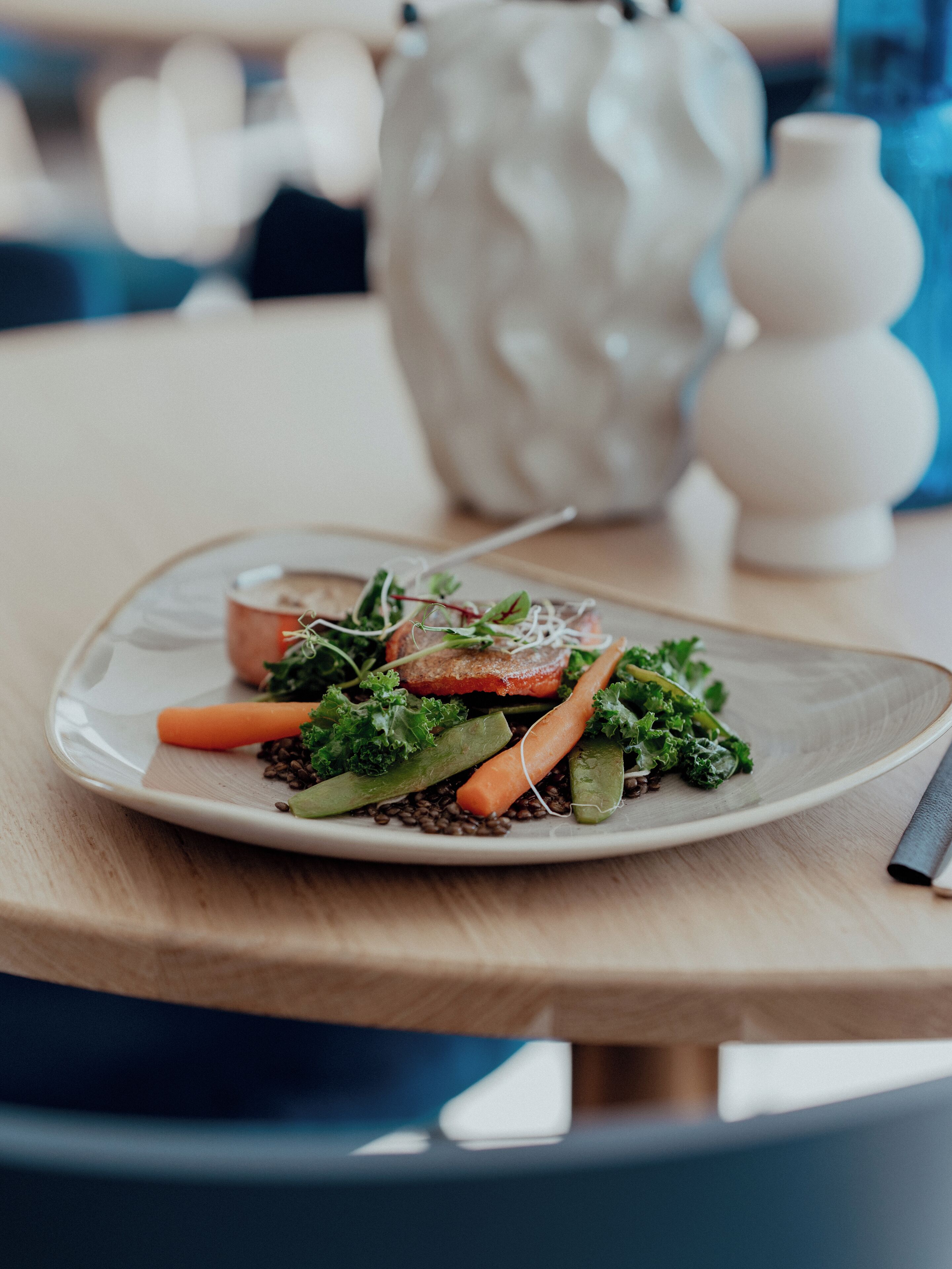 A plate of food on a table with a vase and a candle in the background.