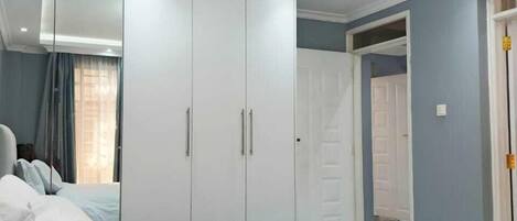 A bedroom with a large bed, white wardrobe, and a ceiling light fixture.