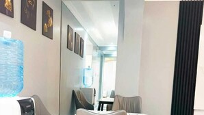A modern dining area with a water dispenser, a large water bottle, and a table with chairs. - Lux Suites Grandville Apartments (Nairobi)