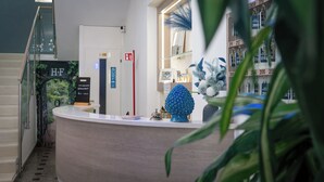 A reception desk with a sign for breakfast, a telephone, and a surf direction sign. - Hotel Fattori (Cesenatico)