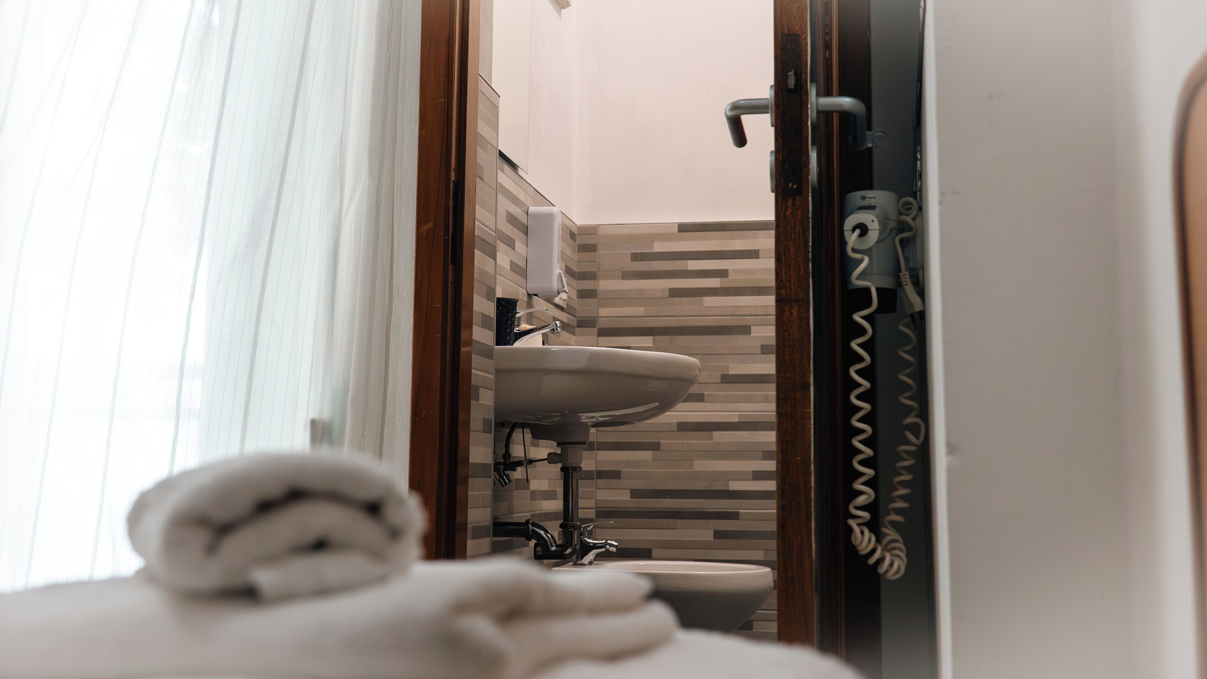 Un baño con lavamanos blanco, inodoro y toalla en el suelo.