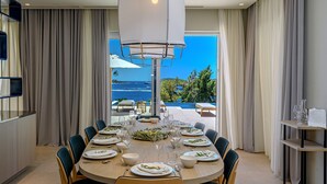 Comedor con mesa dispuesta para seis personas, con vistas a una piscina y al océano.
