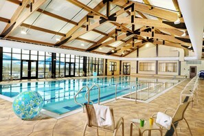 An indoor swimming pool with a high ceiling and natural light from large windows.