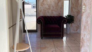 A modern interior with a dark red sofa, a white chair, and a unique white metal structure. A welcome mat with a message is visible.