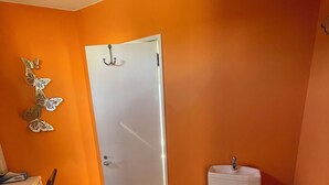 A bathroom with an orange wall, a white toilet, and a white sink.