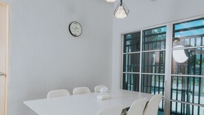 A modern meeting room with a white table and chairs, a clock on the wall, and a large glass door leading outside. - kings Pine Residences HomeStay 3-bedroom house with AC and WiFi in Ranau 14 (Ranau)