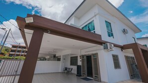 A two-story house with a covered patio, a dining area, and a gate. - kings Pine Residences HomeStay 3-bedroom house with AC and WiFi in Ranau 14 (Ranau)