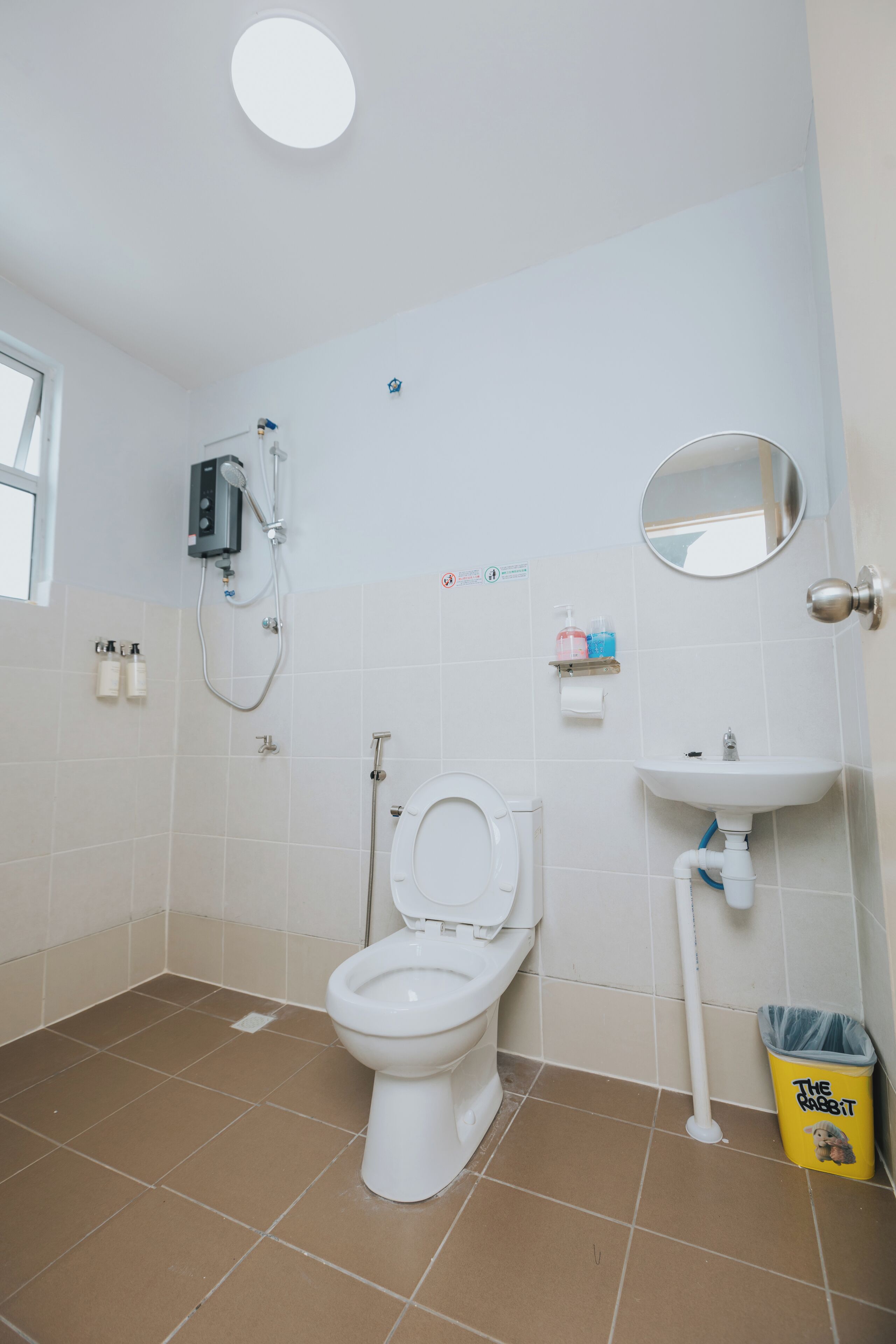 Un baño con inodoro, lavabo, ducha y un cubo de basura.