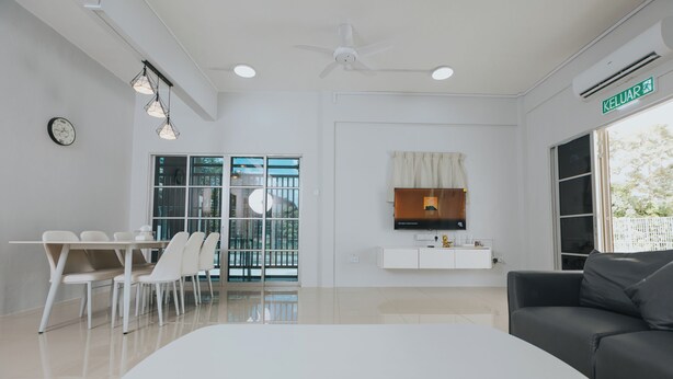 A modern living room with a white sofa, a dining area with a white table and chairs, a TV mounted on the wall, and a ceiling fan. - kings Pine Residences HomeStay 3-bedroom house with AC and WiFi in Ranau 14 (Ranau)