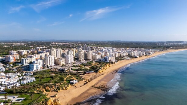 Un paysage urbain côtier avec de hauts immeubles, une plage de sable et une mer bleue et limpide.