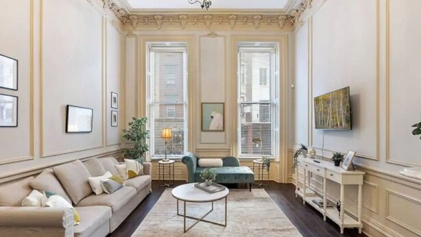 A spacious living room with a sofa, a coffee table, and a television on a stand.