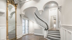 A grand staircase with a black handrail and white balusters, leading to a landing with a white door.