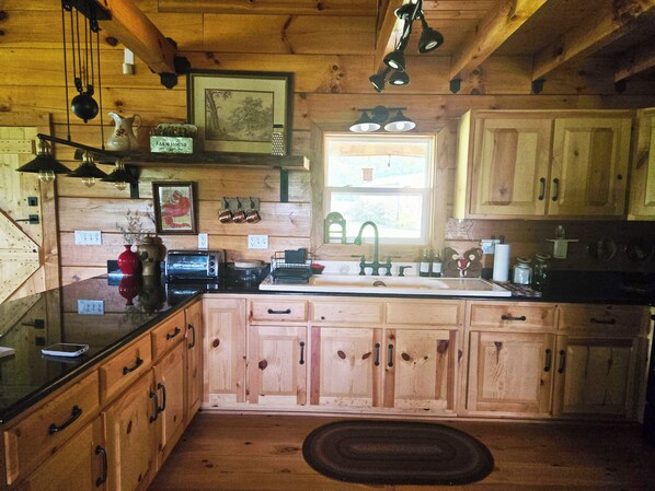 A rustic kitchen with wooden cabinets, a sink, a stove, and a toaster. - Hannah's Hideaway - Sleeps 6, secluded cabin in Stuart with mountain views (Stuart)