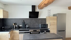 Une cuisine moderne avec des meubles en bois, un four encastré, un four à micro-ondes et un réfrigérateur en acier inoxydable.