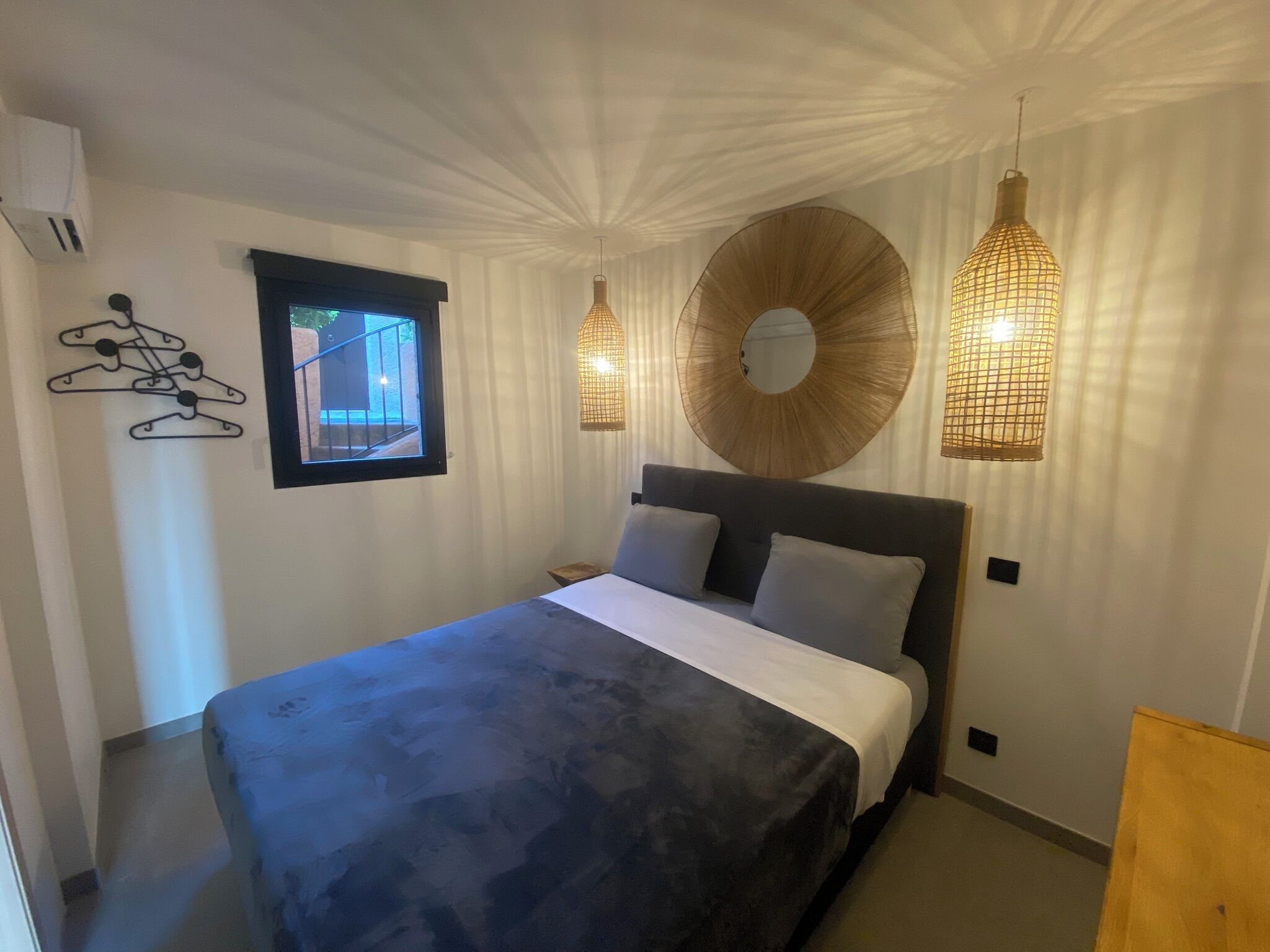 Een slaapkamer met een bed, een raam en twee hanglampen.