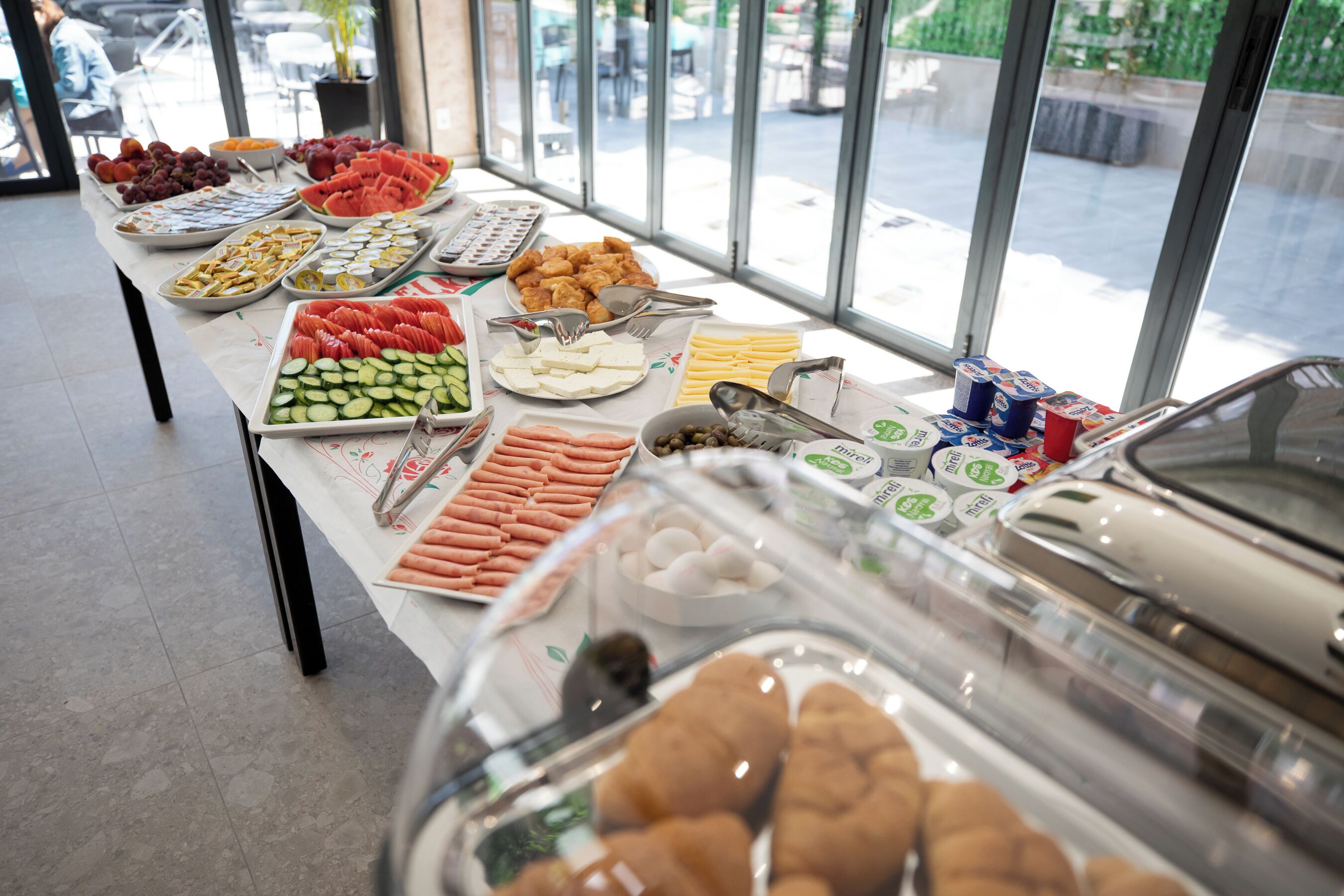 A buffet table with various food items and a glass display case with pastries.
