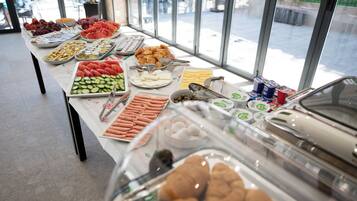 A buffet table with various food items and a glass display case with pastries.