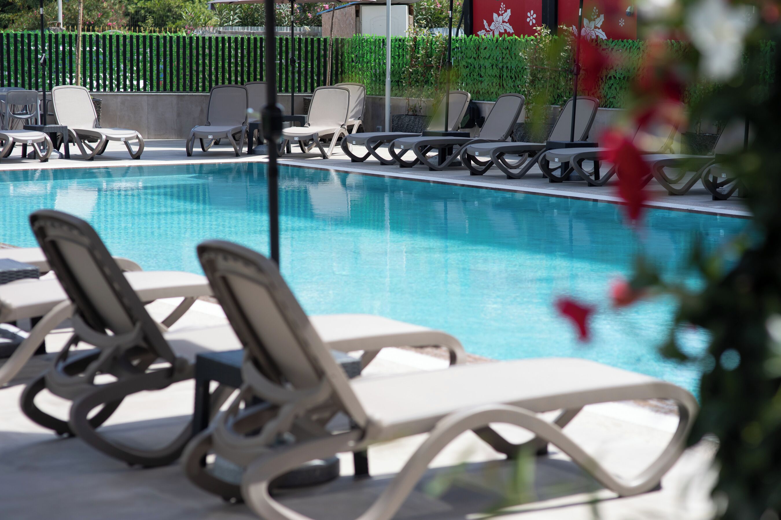 Un espace piscine avec des chaises longues et une clôture.