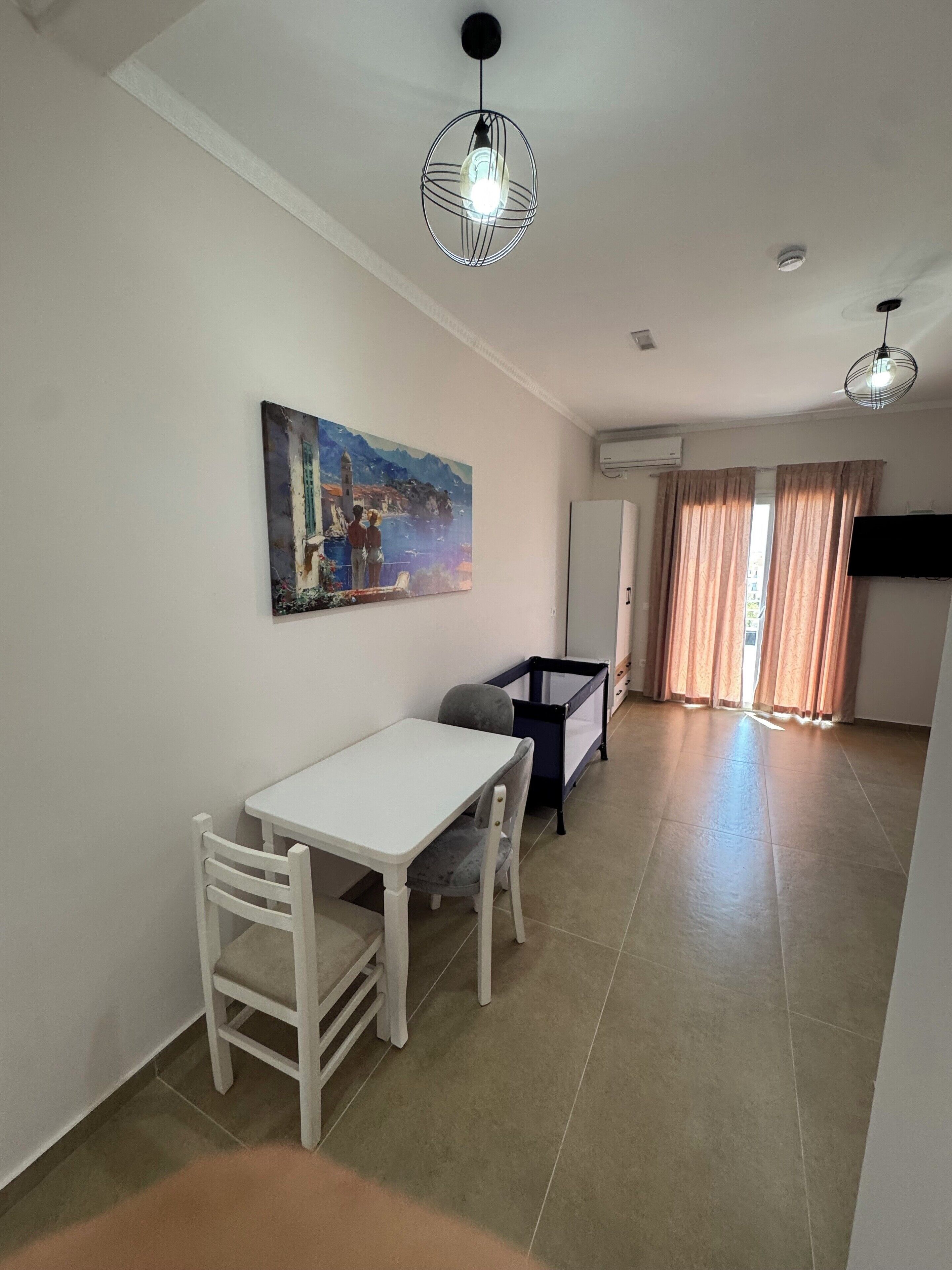 A spacious living area with a dining table, chairs, a sofa, and a painting on the wall.