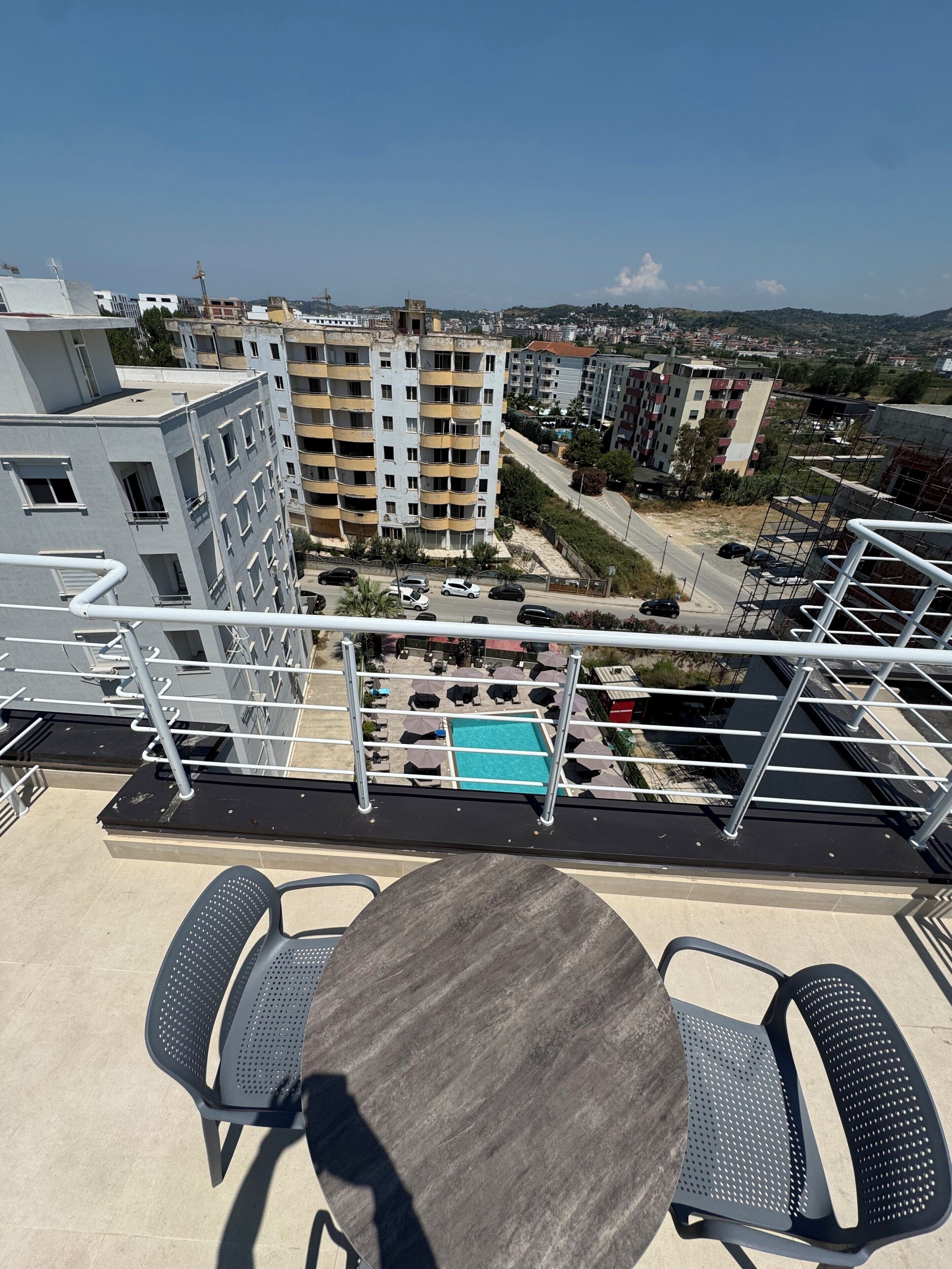 A rooftop terrace with a pool, outdoor seating, and a view of surrounding buildings.
