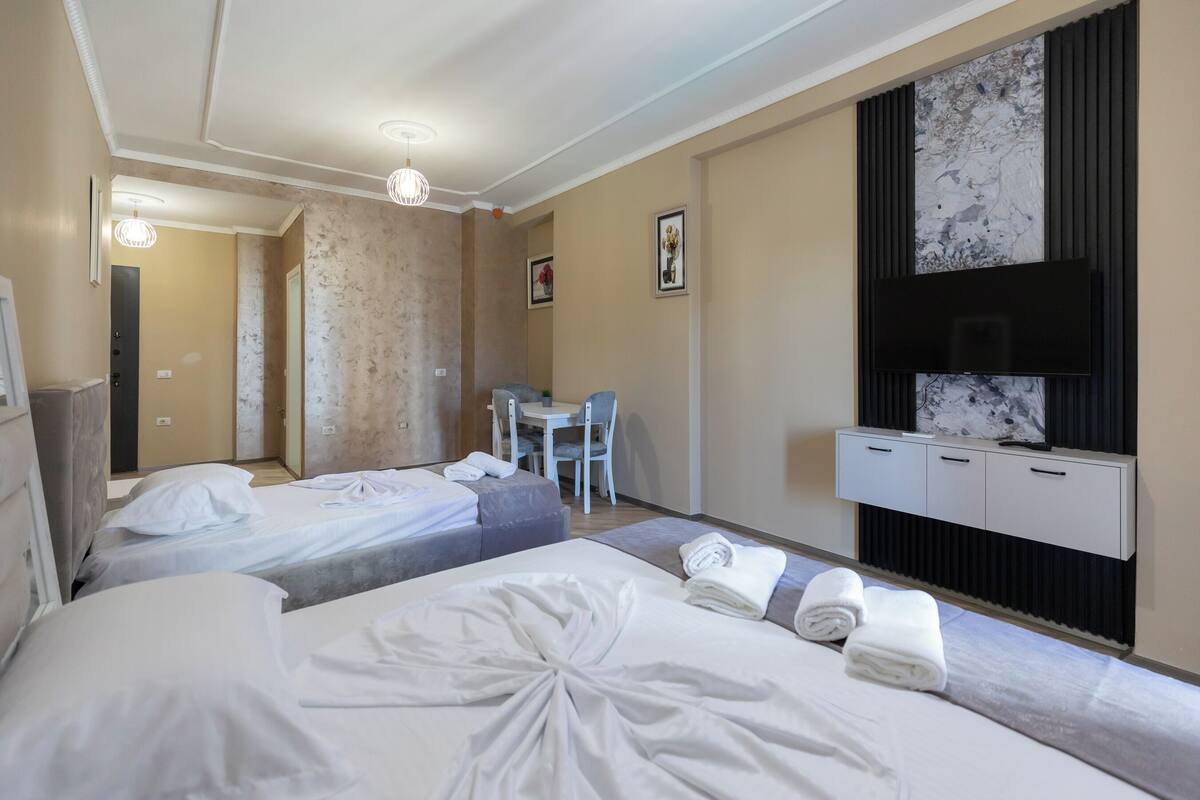 A hotel room with two beds, a desk, a television, and a bathroom visible through an open door.