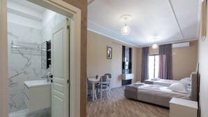 A modern hotel room with a bathroom, a dining area, and a bed.