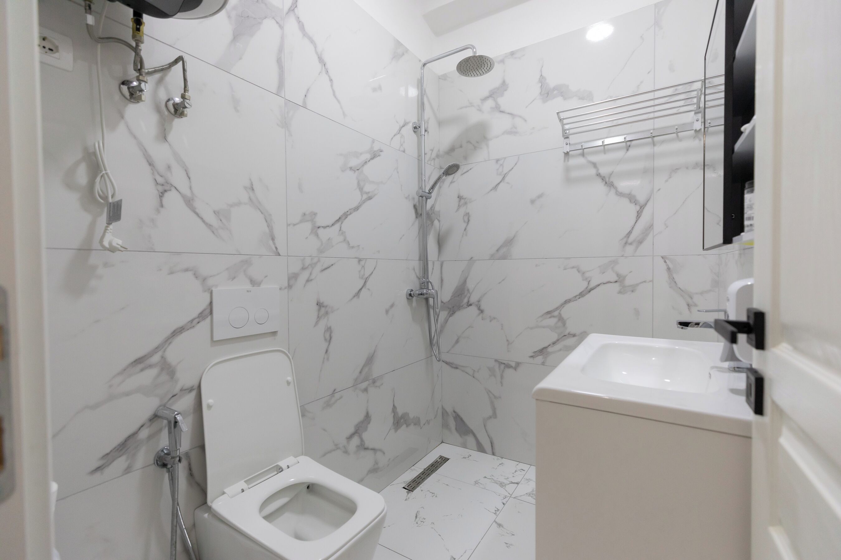 A bathroom with a toilet, shower, and sink.