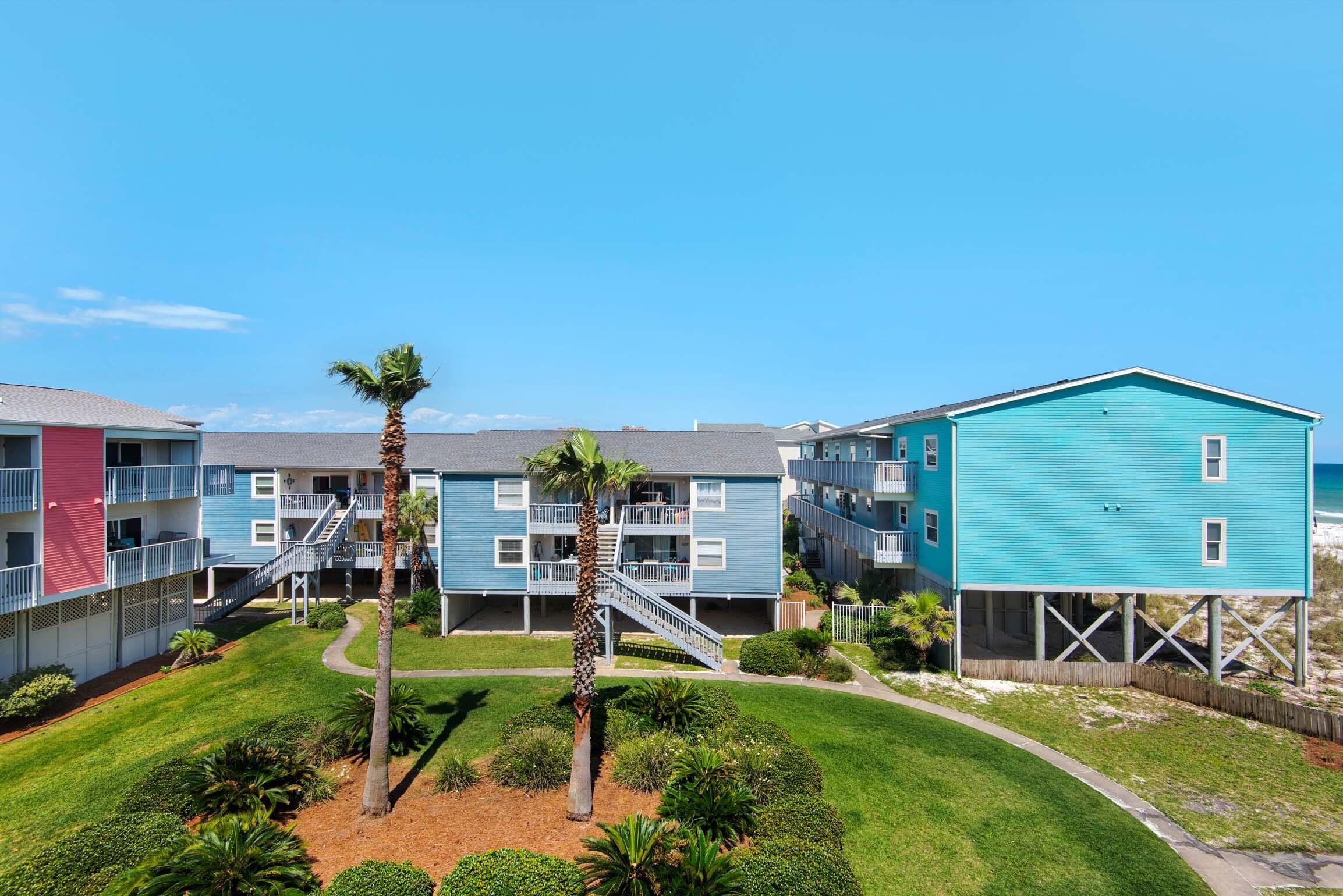 A beachfront hotel with multiple-story buildings, a central staircase, and a sandy beach area.
