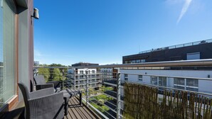 A modern apartment building with multiple balconies, outdoor seating, and a clear view of the surrounding area. - Apartamenty Sun & Snow Golden Tulip (Miedzyzdroje)