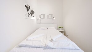 A neatly made bed with white linens, a world map on the wall, and bedside lamps. - Apartamenty Sun & Snow Golden Tulip (Miedzyzdroje)
