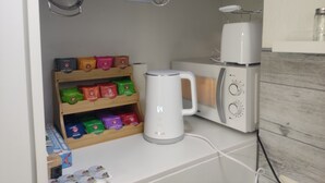 A kitchen with a coffee maker, a microwave, and a shelf with tea bags. - Apartment Classic (Jülich)