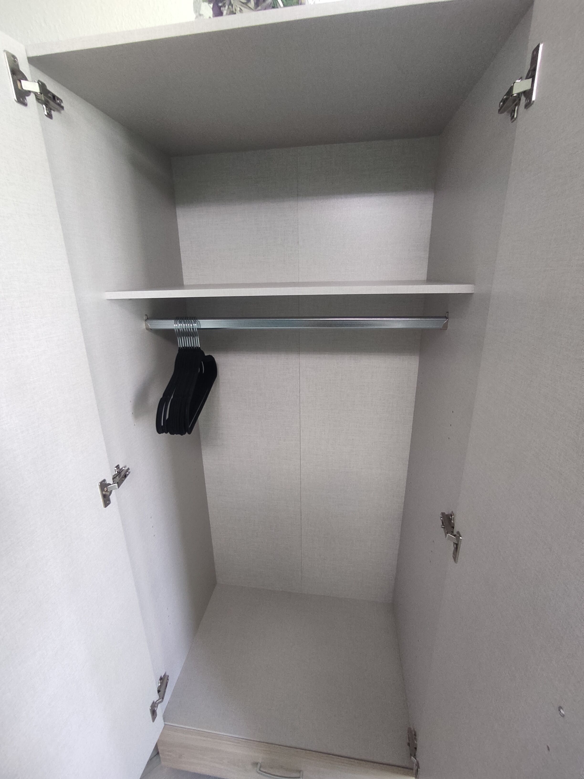 Ein weißer Kleiderschrank mit Ablagefläche und Kleiderstange.