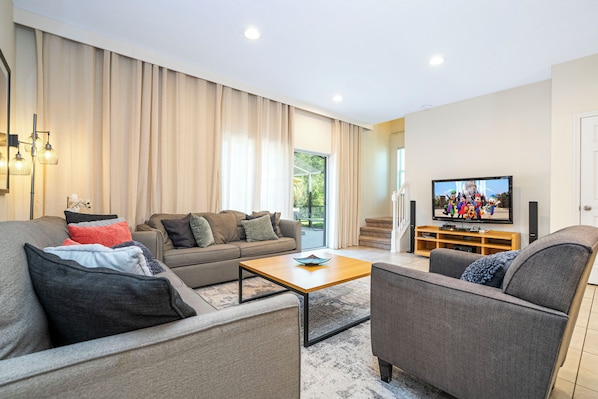 Ein modernes Wohnzimmer mit Sofa, Sessel und Couchtisch, einem Flachbildfernseher sowie einer Holz-Unterhaltungseinrichtung.