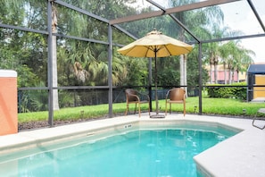 Ein Poolbereich mit Glasveranda, zwei Korbstühlen und einem gelben Sonnenschirm.