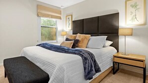 A bedroom with a large bed, a bedside table, a bench, a window with a view, and a wall-mounted lamp. - Family-Friendly 3BR Townhome at Encantada Resort ● Pool, BBQ & Near Disney! (Kissimmee)